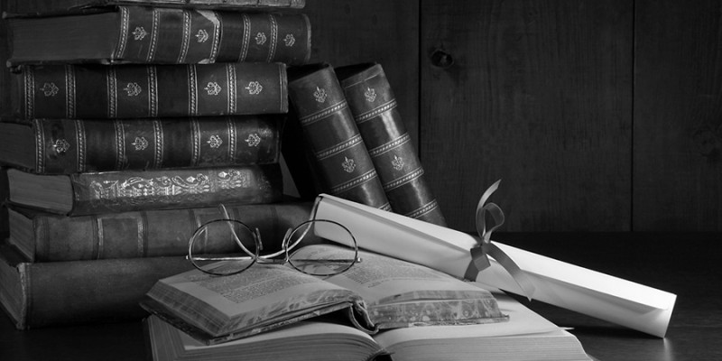 Pile of old books with glasses on desk